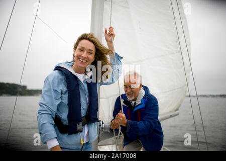 Reifen erwachsenen Frau hissen die Segel für ein Boot mit Ihrem älteren Ehemänner helfen. Stockfoto