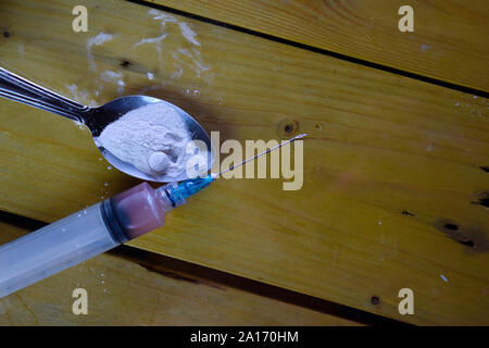 Spritze und Indonesien, rupiah und Kokain bereit für Verwendungen auf Holztisch. Kokain Drogensucht Konzept Stockfoto