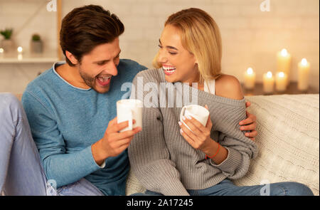 Paar lachend auf der Couch sitzen, Kaffee trinken Indoor Stockfoto