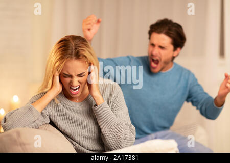 Gewalttätigen Ehemann schrie Frau sitzt auf der Couch zu Hause Stockfoto