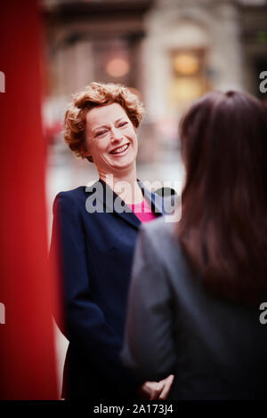 Unternehmerinnen im Gespräch neben einem roten Telefonzelle. Stockfoto