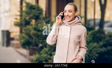 Glücklich lächelnde Frau mit Handy im Freien in der Stadt Stockfoto