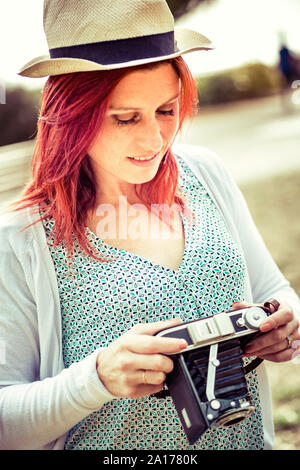 Porträt eines attraktiven Lächeln redhead Anpassungen auf Ihre alte Kamera. Jahrgang Behandlung Stockfoto