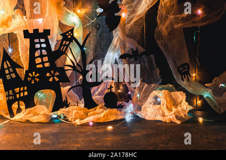 Witch's Haus mit einem schwerwiegenden und ein unheimlich Baum aus schwarzem Papier geschnitzt auf einer hölzernen Wand mit einem Spinnennetz und LED-Kranz. kopieren. Basteln für Halloween c Stockfoto