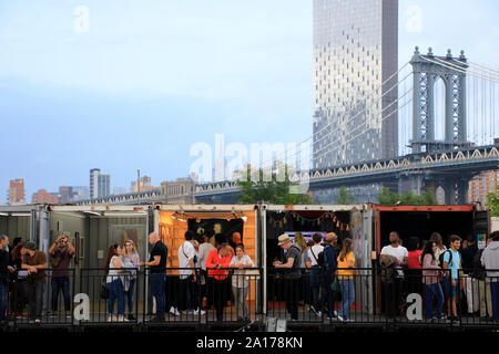 Besucher in jährlichen Photoville Fotografie Kunst Ausstellung mit Manhattan Bridge im Hintergrund in Brooklyn Bridge Park. Brooklyn New York USA Stockfoto