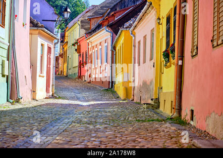 Bunte erhaltenen Fassaden mit gepflasterten Straße bergauf in der Zitadelle von Sighisoara, Rumänien. Sighisoara, Rumänien - Juli 2019. Stockfoto