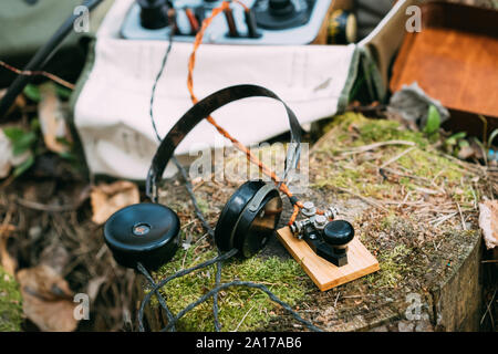 Russisch-sowjetischen Tragbares Radio Transceiver von udssr Red Army Signal Corps im Zweiten Weltkrieg verwendet. Kopfhörer und Fernschreiber Key sind auf einem Baumstumpf. Stockfoto