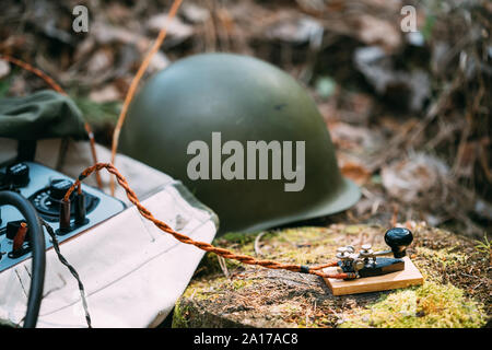 Russisch-sowjetischen Tragbares Radio Transceiver von udssr Red Army Signal Corps im Zweiten Weltkrieg verwendet. Fernschreiber Schlüssel und Helm sind, auf einem Baumstumpf. Stockfoto