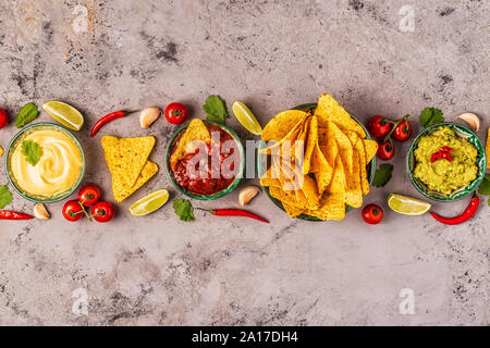 Mexikanisches Essen Hintergrund: Guacamole, Salsa, cheesy Soßen mit Nachos, Ansicht von oben. Stockfoto
