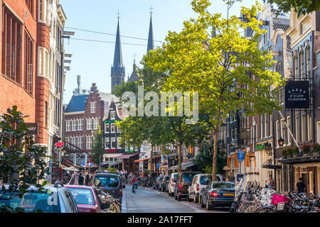 Spuitstraat mit typisch holländischen Häusern, der Verkehr, die geparkten Autos und Fahrräder an einem sonnigen Nachmittag. Amsterdam, Niederlande. Stockfoto