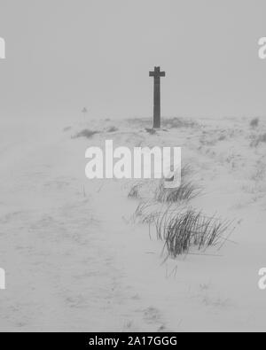 Ralphs Kreuz auf Danby Hochmoor in der North York Moors National Park im Winter. In der Umgebung des Kreuzes ist im Schnee Stockfoto