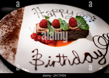 Eine erstaunliche Chocolate Brownie mit Himbeeren und Minze und Happy birthday in Schokolade geschrieben eingerichtet Stockfoto