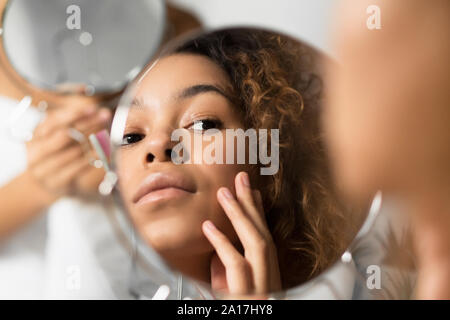 Afro Frau im Spiegel berühren Gesicht an Bad Stockfoto
