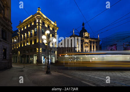 Mailand, Italien - 18. März 2017: Palazzo delle Assicurazioni Generali in Piazza Cordusio in der Dämmerung, im Vordergrund licht Trail durch die Straßenbahn links Stockfoto