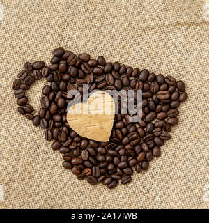 Kaffeebohnen in der Form einer Kaffee Tasse mit geschnitzten Herz auf natürliche Leinwand, einen Sack. Konzept der Kaffee lieben, lieben Stockfoto
