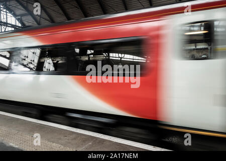 Beschleunigung Zug passiert Bahnhof Plattform. Großbritannien Stockfoto