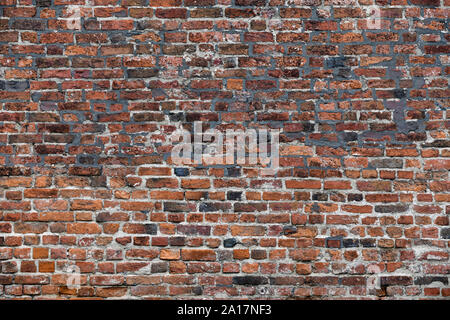 Old Red Brick Wall mit viel Struktur und Farbe. Stockfoto