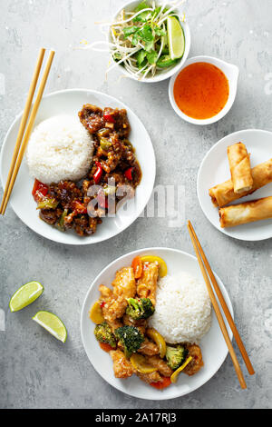 Chinesisches Essen auf dem Tisch mit Rindfleisch, orange Chicken und Frühlingsrollen Stockfoto