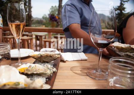 Brille mit glitzernden rosa Wein und ein weiteres mit Rotwein auf dem Holztisch zum Koppeln mit Austern in Gourmet Stil gekocht platziert Stockfoto