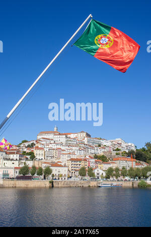 Blick auf die Altstadt von Coimbra aus Santa Clara Brücke mit Portugal Flagge das Weben in den blauen Himmel. Coimbra ist eine wunderschöne historische Stadt mit vielen touristischen sp Stockfoto