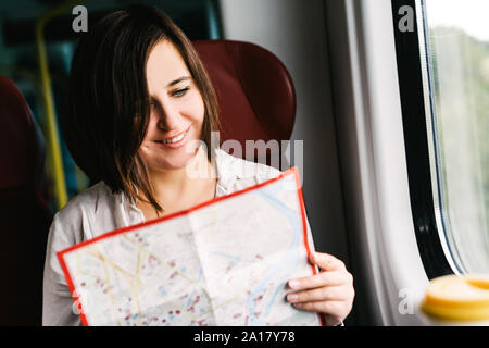 Eine lächelnde Frau in einen s-bahn Studien die Karte und lächelt. Stockfoto