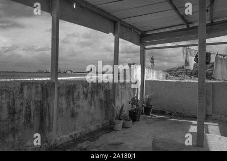 Schwarzer Mann auf einem bleacher in einem Slum an der Küste von Olinda. Stockfoto