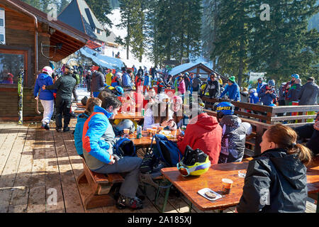 Poiana Brasov, Rumänien - 20. Februar 2019: Skifahrer und Snowboarder auf Julius Romer Hutte/Postavaru Hütte Terrasse, an einem sonnigen Tag im Winter. Stockfoto