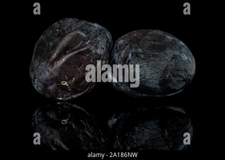 Gruppe von zwei ganze Trocknen dark blue Plum auf schwarzem Glas isoliert Stockfoto