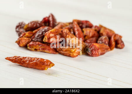 Menge ganze trockene rote Chili peperoncino Heap auf weißem Holz Stockfoto