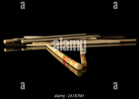 Menge ganze gekreuzt asiatischen braun Essstäbchen auf schwarzem Glas isoliert Stockfoto