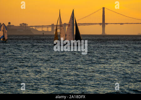 Zwei küssen Segelboote unter der Golden Gate Bridge bei Sonnenuntergang. Stockfoto