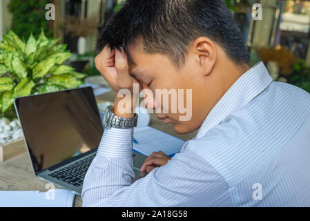 Frustrierte junge Unternehmer in Kopfschmerzen während der Arbeit am Laptop Stockfoto