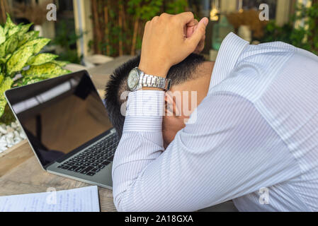 Frustriert asiatische Geschäftsmann holding Kopf während der Arbeit am Laptop Stockfoto