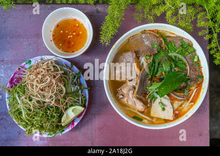 Schüssel mit köstlichen vietnamesischen Rindfleisch nudeln Suppe und Gemüse Stockfoto
