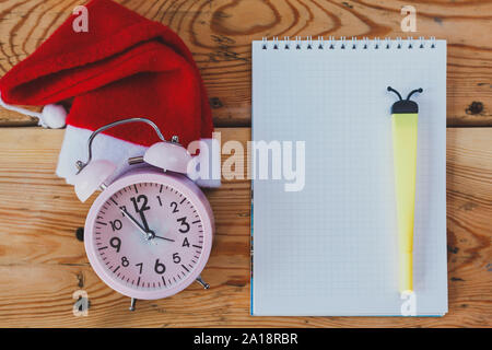 Weihnachten und neues Jahr Hintergrund. Leere Notizblock, Stift und Santa hat. Weihnachten Wunschliste. Brief an den Weihnachtsmann. Xmas-to-do-Liste. Weihnachten Konzept. C Stockfoto