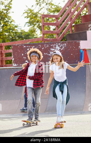 Zwei glückliche Freunde Spaß beim Reiten auf Skateboards zusammen in den Park im Freien Stockfoto