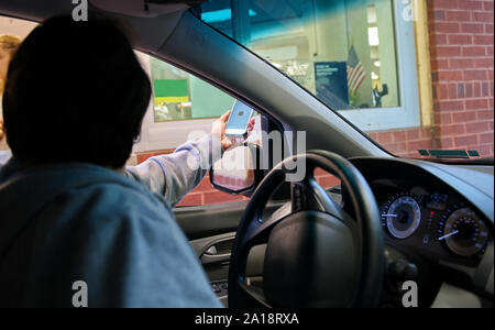 Smartphone in der Hand als Antrieb in Kunden für ihre Medikation an der lokalen Apotheke zahlt. Stockfoto