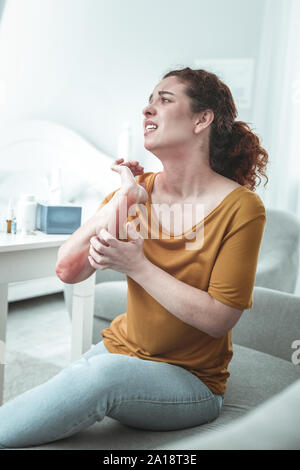 Frau Gefühl schrecklich mit Kratzern und Rötung auf ihrem Arm Stockfoto