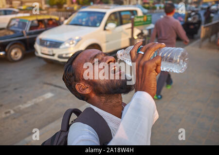 Ein Mann in Mumbai, Indien, Getränke Wasser aus der Plastikflasche, in Übereinstimmung mit den lokalen Gewohnheit oder Konzept von Reinheit, ohne seine Lippen berühren der Flasche Stockfoto