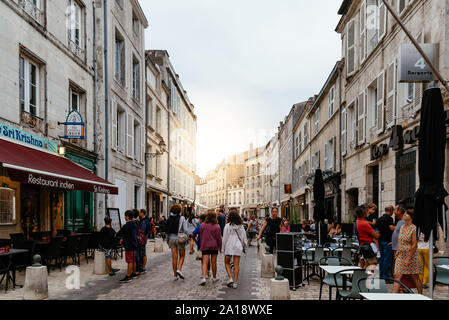 La Rochelle, Frankreich - 7 August, 2018: die Menschen an belebten Straße mit Restaurants in der Nähe des Old Port. Sun flare auf Hintergrund Stockfoto