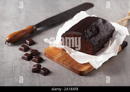 Köstliche frische hausgemachte dunkle Schokolade Banane Brot mit rustikalen Messer am grauen Stein Hintergrund. Stockfoto
