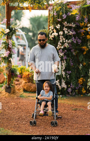 Asiatische Vater mit Kind im Kinderwagen im Park Bärtigen. Stockfoto