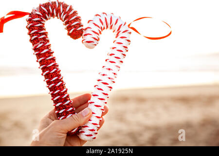 Frau mit Weihnachten Zuckerstangen bei Sonnenuntergang am Strand, Saison urlaub Konzept - Bild Stockfoto