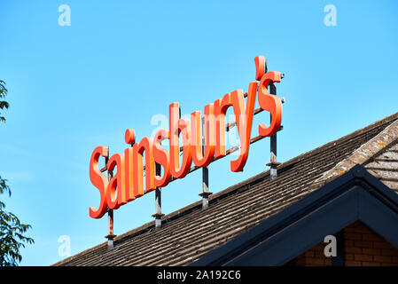 Zeichen über den Sainsbury's Supermarkt im Einkaufszentrum in Corby, Northamptonshire, England, an einem sonnigen Tag. Stockfoto