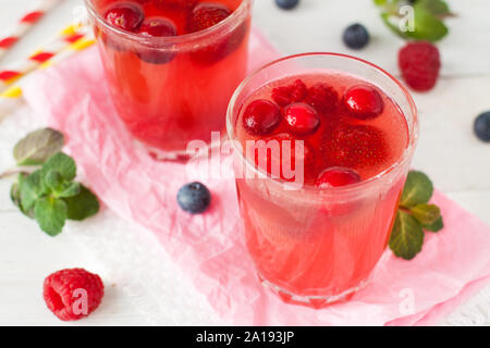Frische rosa Limonade mit Himbeere, Preiselbeere, Erdbeere, Apfel, Limette mit Minze auf weißem rustikalen Tisch dekoriert Stockfoto