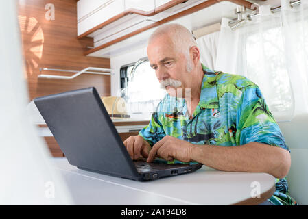 Ältere Menschen mit lapto in seinem Van Stockfoto