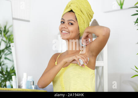 Junge Frau die Walze deodorant in Ihrer Achselhöhle Stockfoto