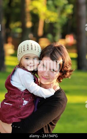 Eine Mutter und ihre ein Jahr alte Tochter Umarmen im Sommer Park Stockfoto