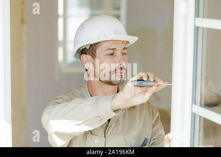 Service Mann Installation Fenster mit Schraubendreher Stockfoto