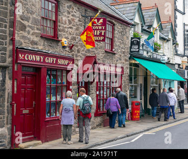 Fußgänger in Windows der Souvenirladen und Fisch und Chip Shop, Castle Street, Conwy oder Conway, Conwy County, Wales, Vereinigtes Königreich. Stockfoto